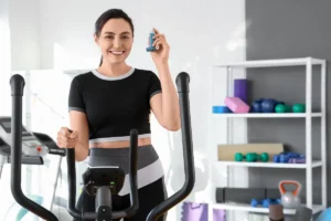 Woman on elliptical trainer holding a asthma inhaler in McKinney, TX